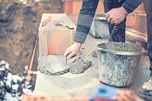 Mason working with construction spatula and leveling mortar for creating walls. Soft effect on photo