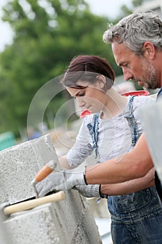 Mason with young woman trainee at work