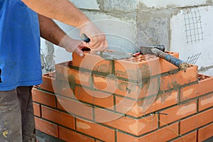 Masonry brickwork. A masonry contractor is laying the house corner with face bricks bonding them with a concrete block wall with a