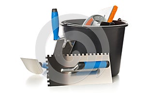 Masonry tools - trowels, notched trowel and mortar bucket - on w