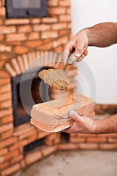 Masonry worker hands with brick and clay mortar on trowel
