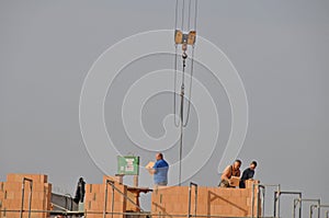 Masons laying bricks standing high on scaffolding