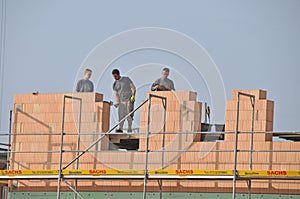 Masons laying bricks standing high on scaffolding