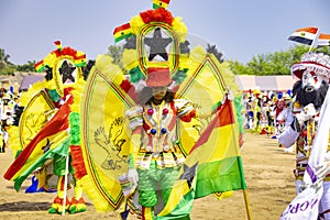 Masquerade and fancily dressed festival participant with Ghana flag dudring a festival