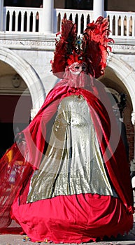 masquerade woman during the Venice carnival in Italy with long historical dress and the palace in the background