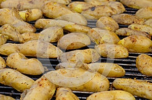 Mass of potato halves in peels baking on a grill