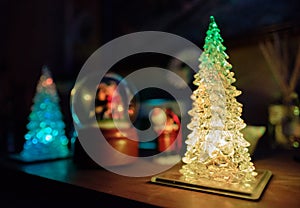 Mass produced, battery powered pine tree toys seen on a table in a home.