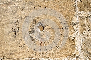 Mass or scratch dial with Roman numerals on a stone church wall in Bibury