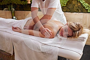 Massage and body care. Young lady with tan or honey skin receiving relaxing massage