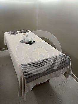 a massage cabin prepared to attend a client, with a massage table with towels, essential oils and creams for massage