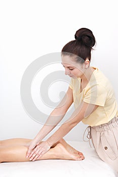 Massage and kneading of the client`s ankles and lower legs. Studio vertical shot in which a masseuse smoothes muscles and skin