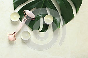 Massage roller on a monstera leaf, candles, top view