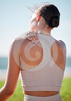Massage, shoulder pain and fitness with woman at beach for yoga, workout and exercise training. Burnout, injury and