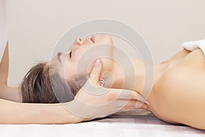 Massage and stretching of the cervical muscles. Beautiful girl gets massage in a spa salon. light tones photos.