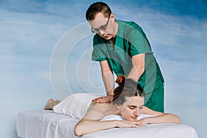 Massage therapist doing massotherapy of a young woman. Beautiful relaxed face of a young woman