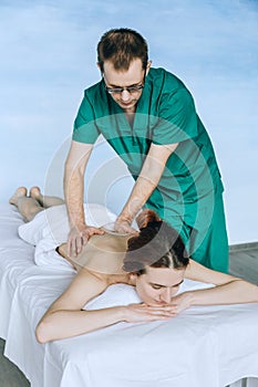 Massage therapist doing massotherapy of a young woman. Beautiful relaxed face of a young woman with brown hair and closed eyes