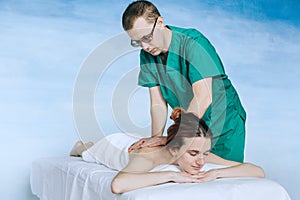 Massage therapist doing massotherapy of a young woman, elbow joint massage. Beautiful relaxed face of a young woman