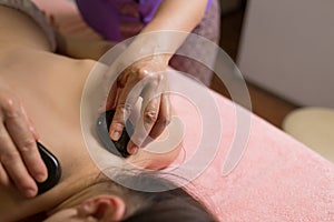 Massage therapist putting spa stones on the back of girl lying on massage table