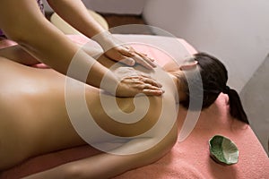 Massage therapist putting spa stones on the back of girl lying on massage table