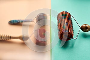 Massager with red, orange and blue drums, metal needles lie behind the glass on a yellow-green surface. Thematic and promotional