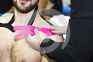 Massaging of young man - kinesiotaping