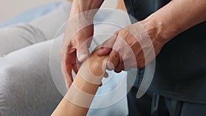 Massagist shaking hand and fingers of young woman