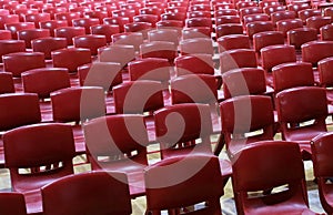 Masses of empty plastic red chairs or seats in a school assembly hall