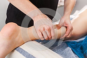 A masseur caressing the legs of a young woman in a spa salon with gentle strokes, offering a moment of relaxation and