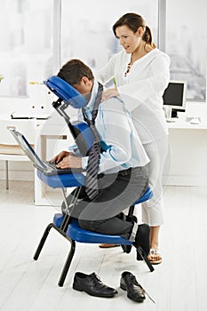 Masseur doing neck massage in office