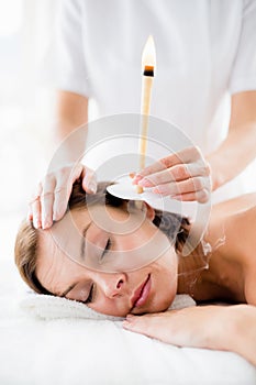 Masseur giving ear candle treament to woman