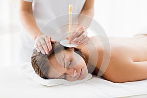 Masseur giving ear candle treatmet to woman