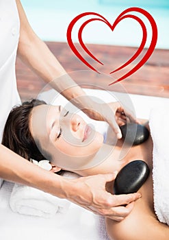 Masseur giving stone massage to woman at spa