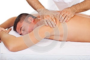 Masseur kneading man back at massage