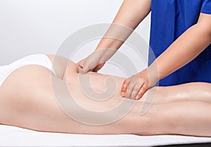 Masseur makes anti-cellulite massageon the legs, thighs, hips and buttocks in the spa. Overweight treatment, body sculpting.