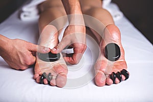 The masseur makes a foot massage with a hot stone.