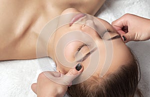 Masseur makes a relaxing massage on the face, neck, shoulders and collarbones of a young beautiful woman in a spa. Cosmetology and