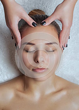 Masseur makes a relaxing massage on the face, neck, shoulders and collarbones of a young beautiful woman in a spa. Cosmetology and