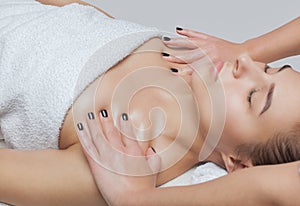 Masseur makes a relaxing massage on the face, neck, shoulders and collarbones of a young beautiful woman in a spa. Cosmetology and