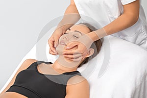 Masseur makes a relaxing massage on the face, neck, shoulders and collarbones of a young beautiful woman in a spa. Cosmetology and