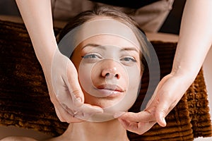 Masseur is making facial massage in spa for model with perfect skin. Beauty procedure.
