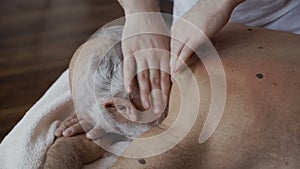 Masseur massages neck to old man