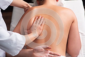 masseur massaging back and shoulder blades of young woman on massage table. Concept of massage spa treatments. Close-up