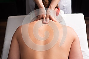 masseur massaging back and shoulder blades of young woman on massage table. Concept of massage spa treatments. Close-up