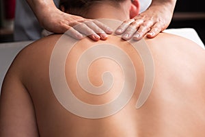 masseur massaging back and shoulder blades of young woman on massage table. Concept of massage spa treatments. Close-up