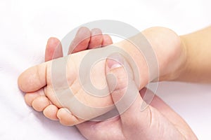 Masseur massaging a small childrens foot. Mother is doing massage on her baby foot.