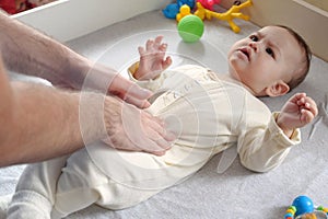 Masseur massaging the tummy of the baby during colic. Mother massaging infant belly, kid laughing