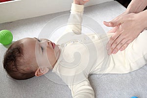 Masseur massaging the tummy of the baby during colic. Mother massaging infant belly, kid laughing