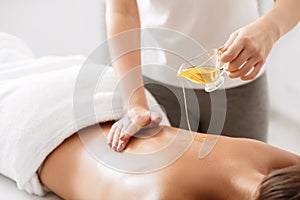 Masseur pouring aroma oil on female back