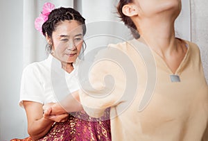 Masseur is pulling woman arm for Massage stretching in Thai Spa