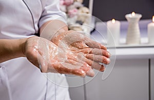 Masseur putting aroma oil on her hands, preparing for massage in spa center
